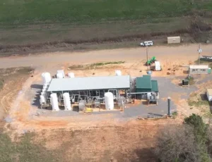 Aerial view of a renewable natural gas facility with multiple storage tanks and equipment surrounded by dirt and grass fields.