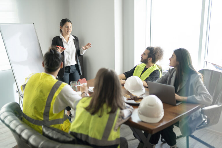 Businesswoman is talking about new project in the meeting room. Her team is sitting around a table and listening their manager carrefully.