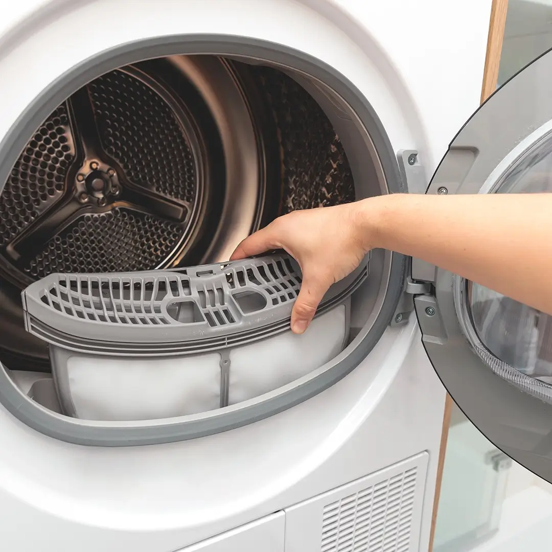 Hand removing lint trap from front-loading dryer.”