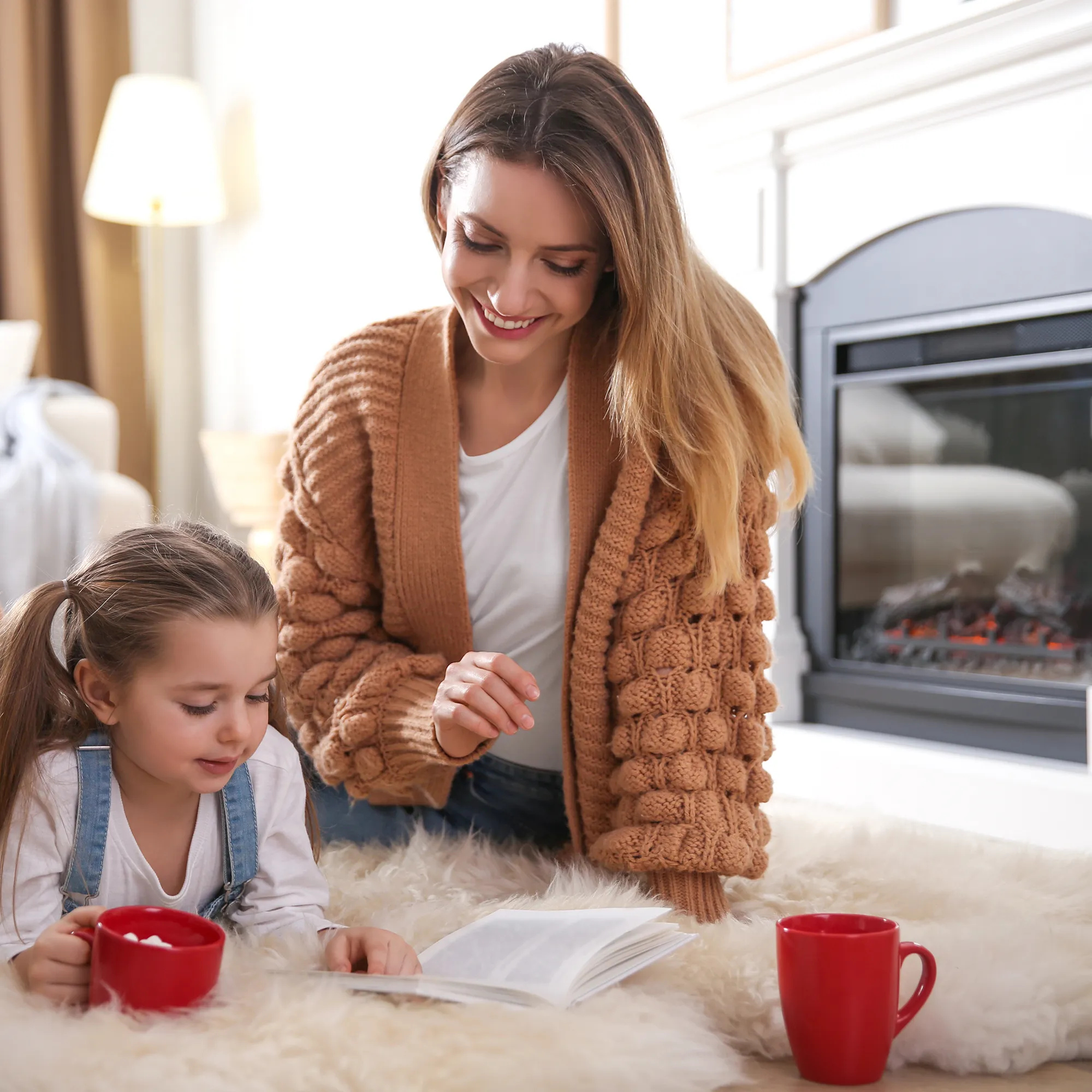 Hand with tongs over a gas grill cooking chicken breasts and kabobs of sausage and veggies