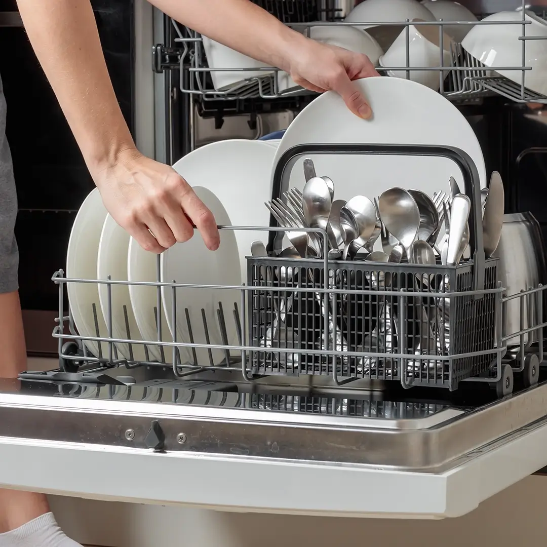 Person unloading clean dishes and silverware from dishwasher.